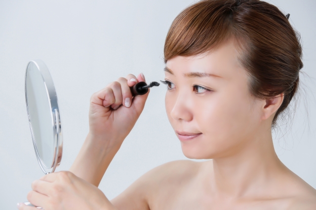 鏡でマスカラを塗る女性